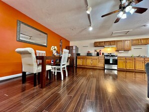 Un comedor con mesa y sillas de madera, una cocina con gabinetes de madera y un ventilador de techo.