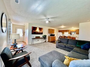 A living room with a sofa, a coffee table, and a TV mounted on the wall. - 240 Overbrook - NEW · Frank's funky and fashionable furnished home (Monroe)