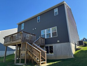 A two-story building with a wooden deck and a staircase leading to the second floor.