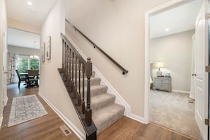 A staircase with carpeted steps and a handrail, leading to a room with a bed and a nightstand. - NEW  Cheerful 5 bedroom home in quiet suburban area. (Maineville)