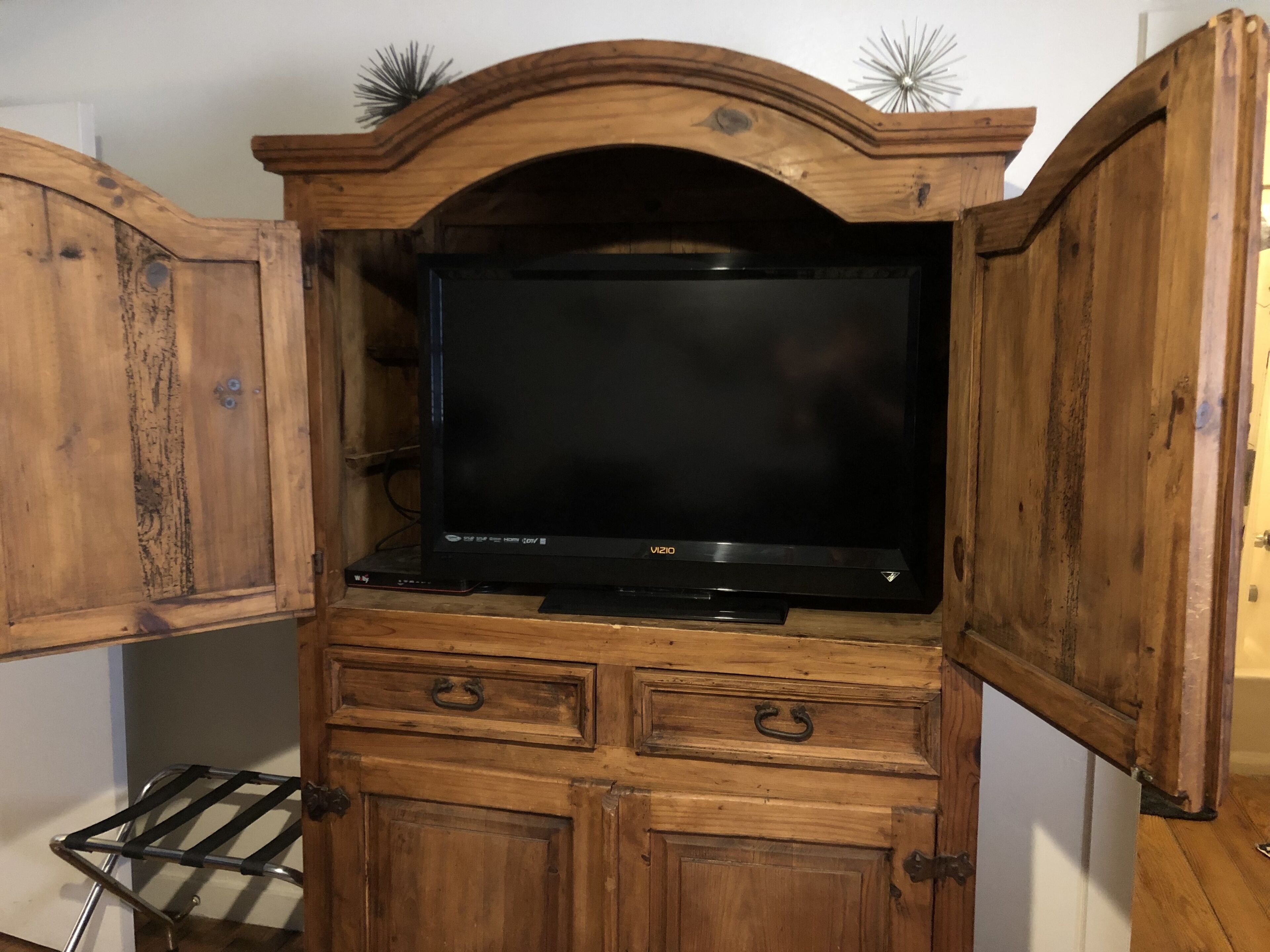 Un meuble de rangement en bois pour appareils multimédias, doté d’un téléviseur à écran plat, de tiroirs intégrés et d’une étagère.