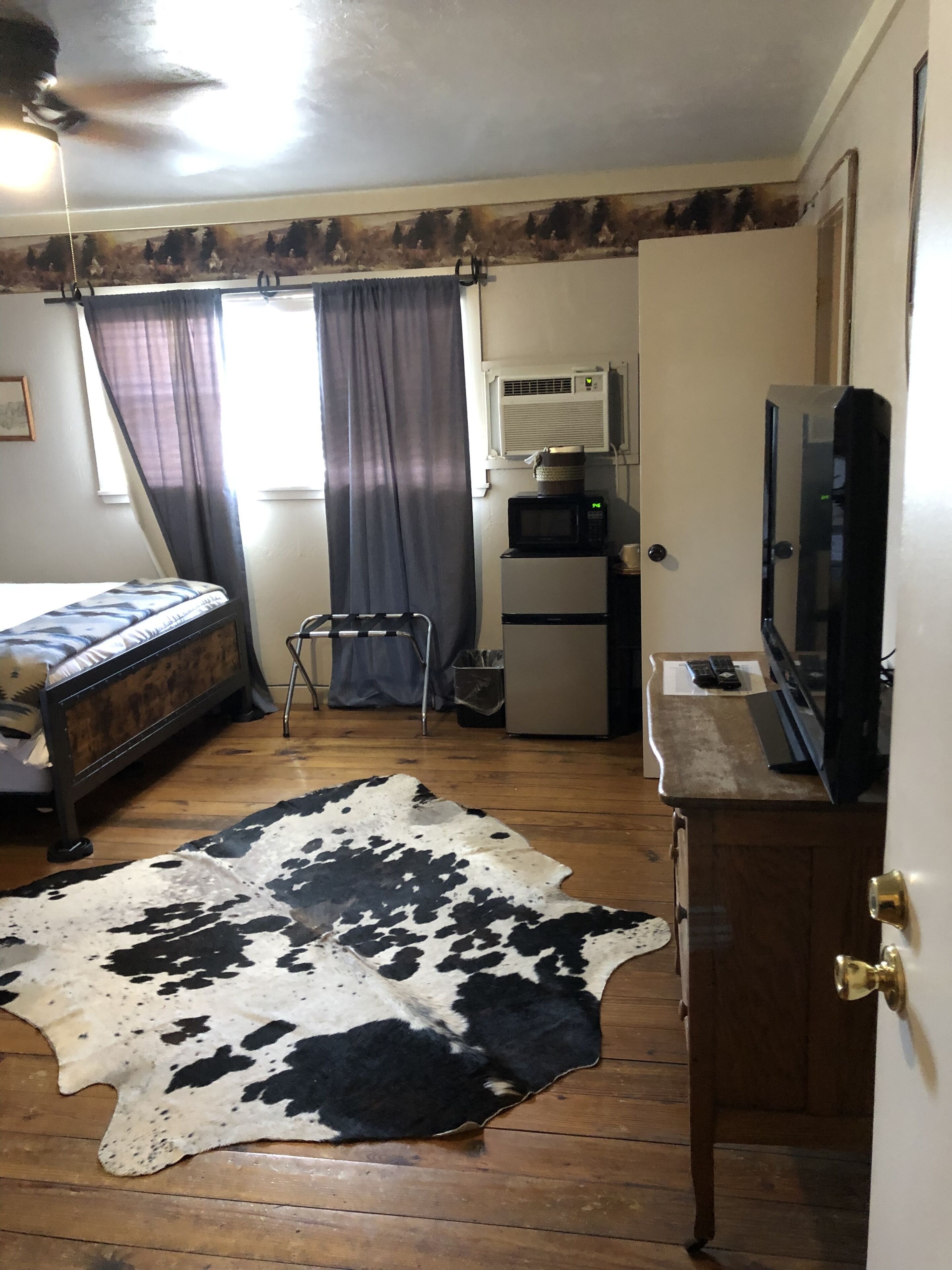 Une chambre équipée d’un lit, d’une télévision, d’un four à micro-ondes et d’un réfrigérateur.