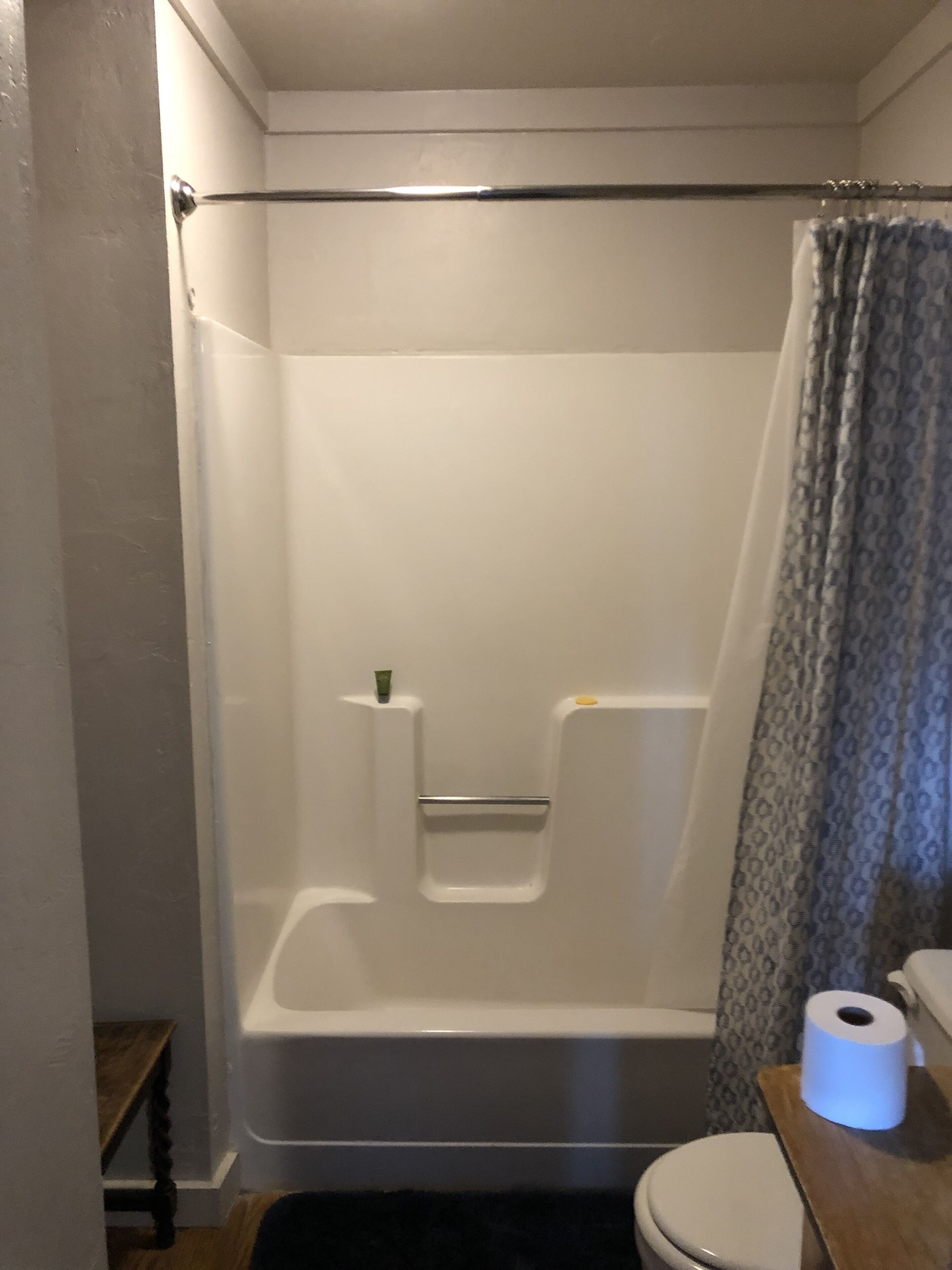 A bathroom with a bathtub, toilet, and a shower curtain.