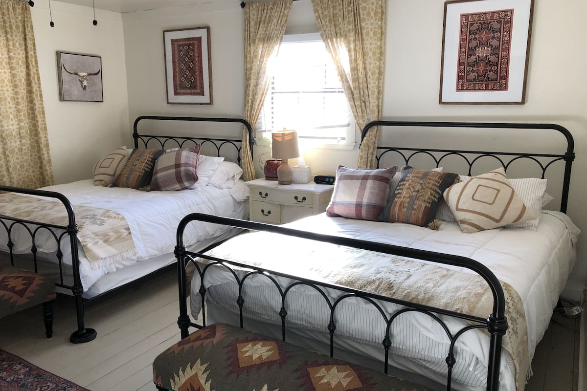 A bedroom with two single beds, a nightstand, a lamp, and patterned curtains.