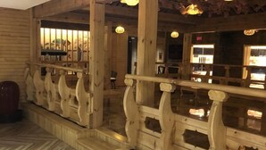 Interior de madera con barandilla, suelo con diseño de espiga y vista al exterior.