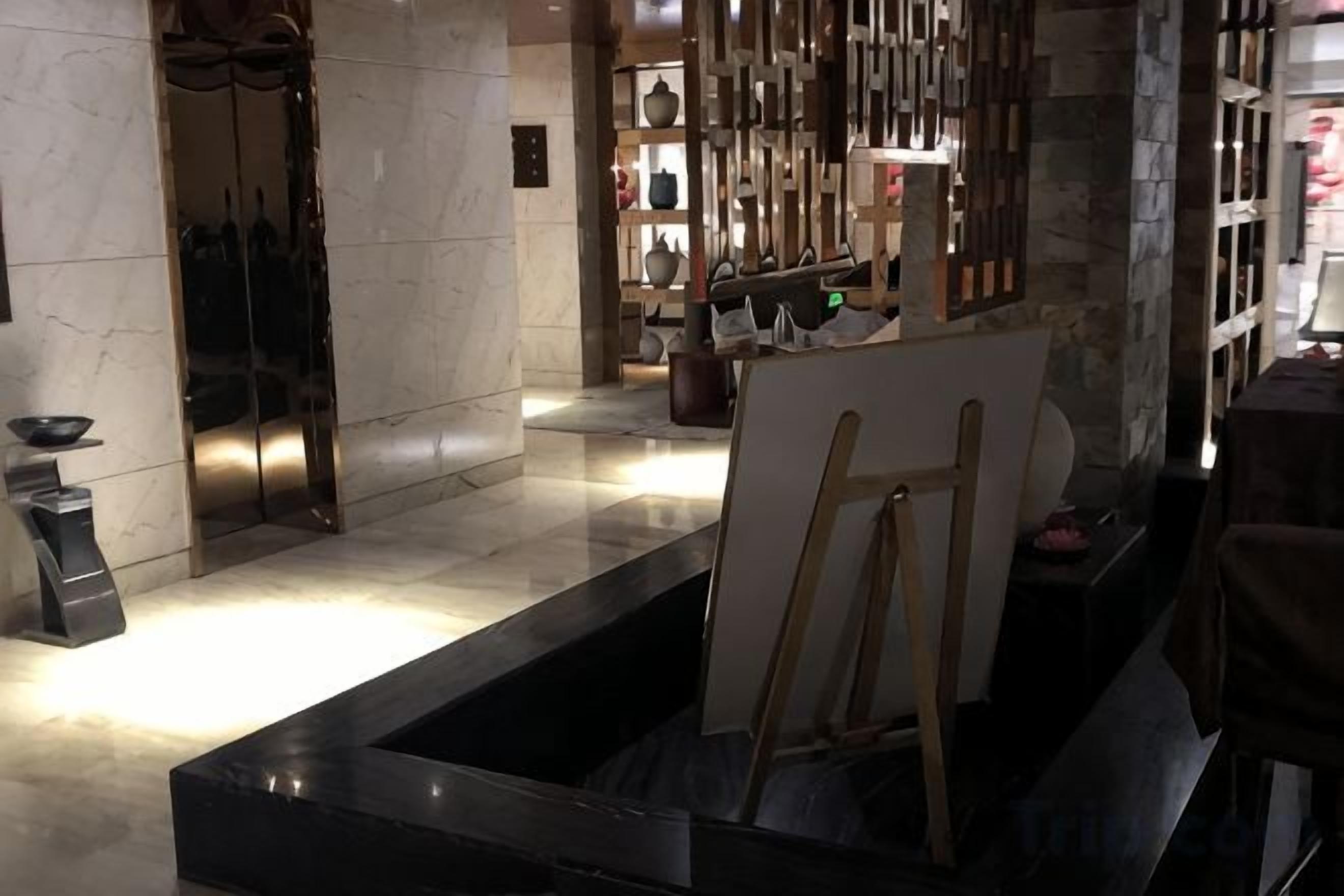 Un área de recepción con mostrador, una zona de estar con mesa y sillas, y una exhibición de objetos decorativos.