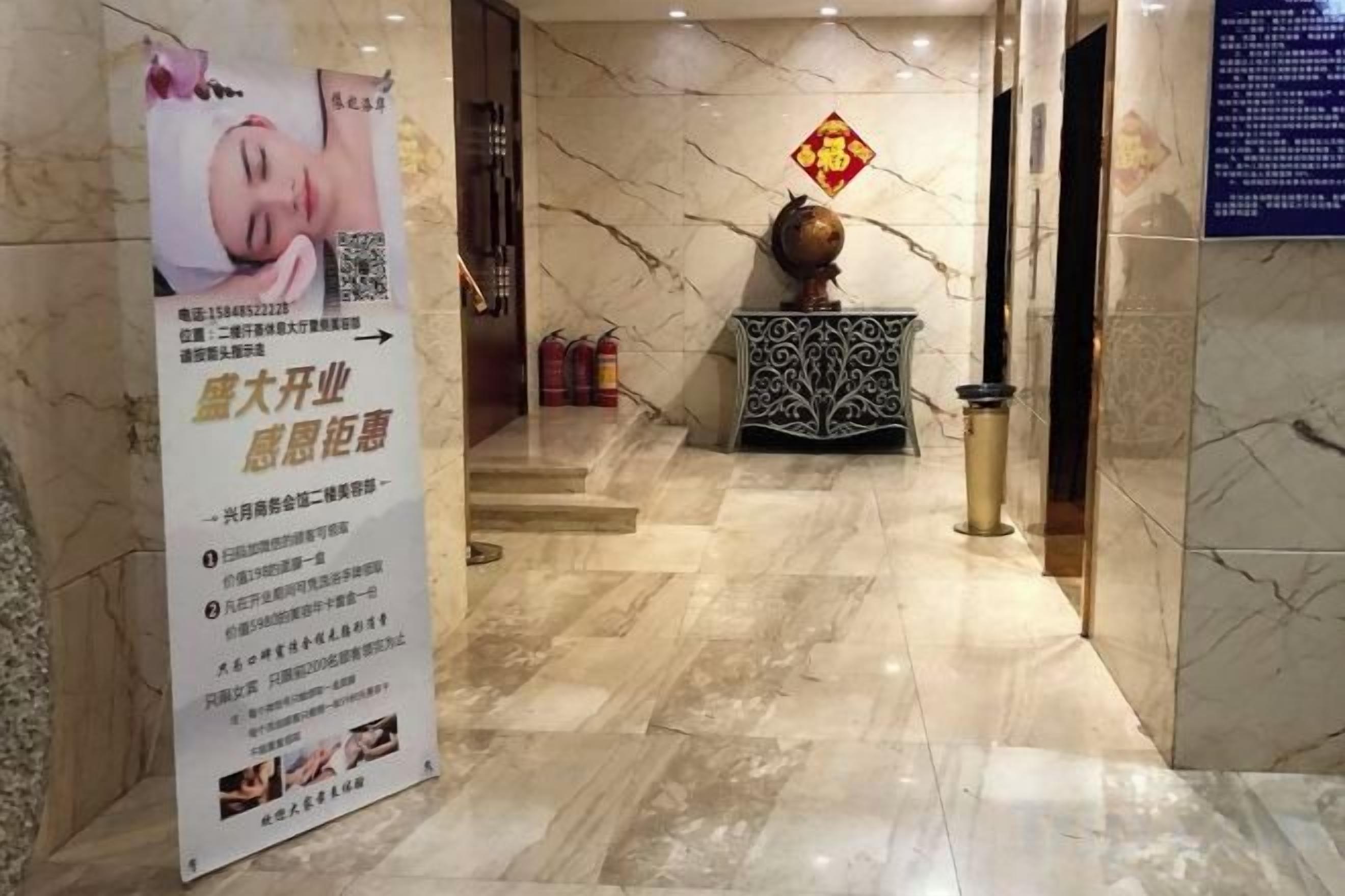 A marble-floored lobby with a reception desk, a decorative vase, and a sign with text.