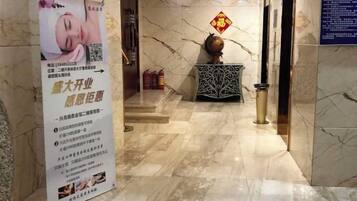 A marble-floored lobby with a reception desk, a decorative vase, and a sign with text.