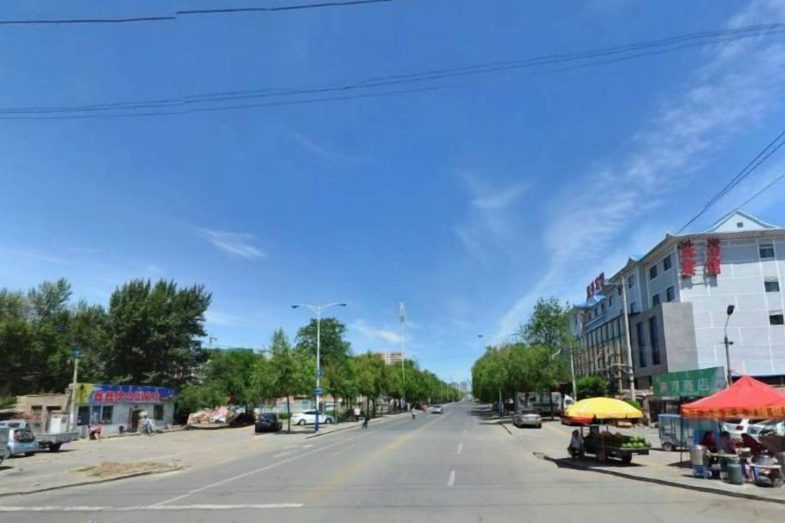 A street view with buildings, a clear sky, and a parked vehicle.