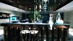 Zona de bar moderna con techo alto, taburetes y una pantalla de televisión.