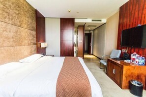 Habitación de hotel con una cama grande, un escritorio con televisor y un panel de pared de madera.