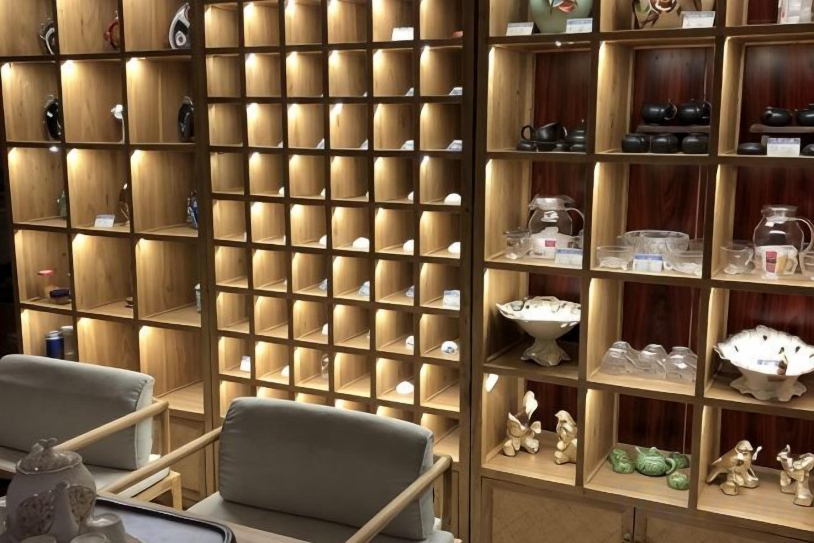 A room with wooden shelving units displaying various items, a seating area with chairs, and a small table.