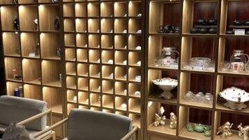 A room with wooden shelving units displaying various items, a seating area with chairs, and a small table.