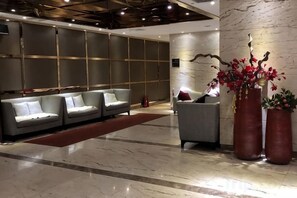 A lobby with a sofa set, a small table, and two large vases with flowers.