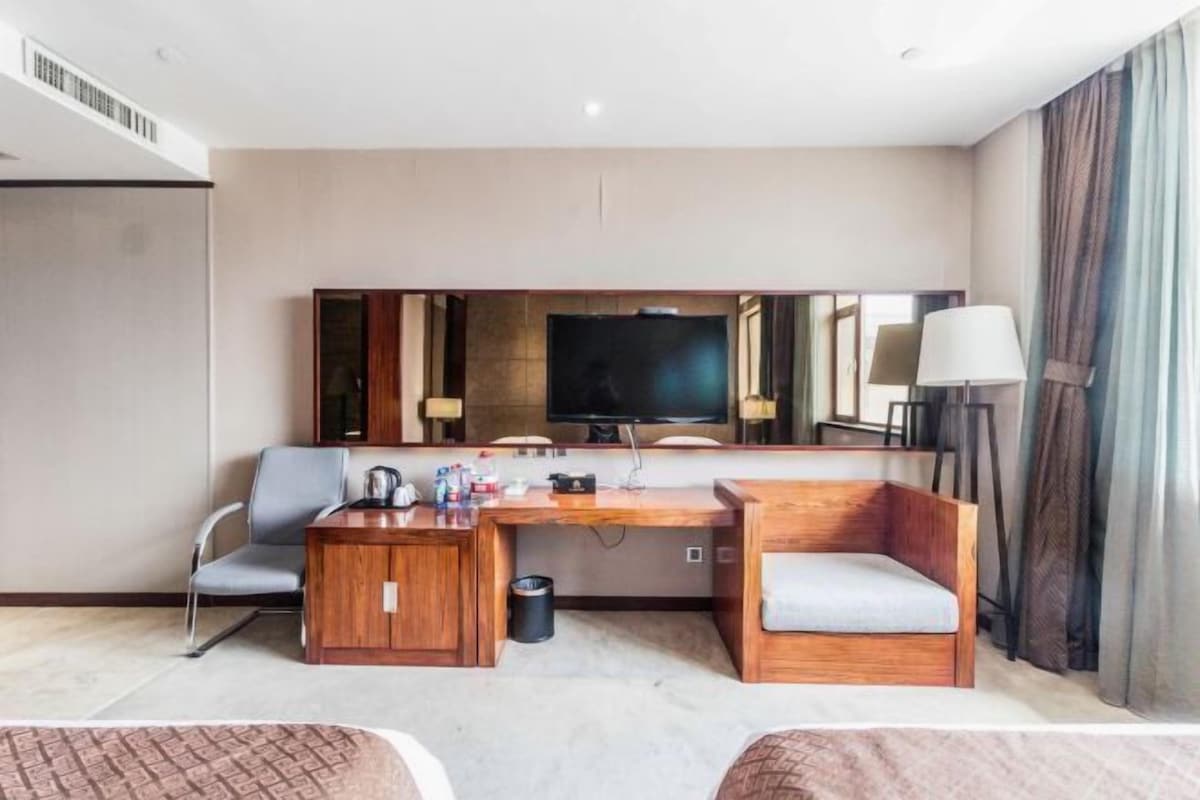 Una habitación de hotel con cama, un escritorio con silla, un televisor y un sofá.