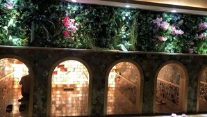 Una pared con un diseño de hojas verdes, tres ventanas arqueadas y una pared de ladrillo con un motivo decorativo.