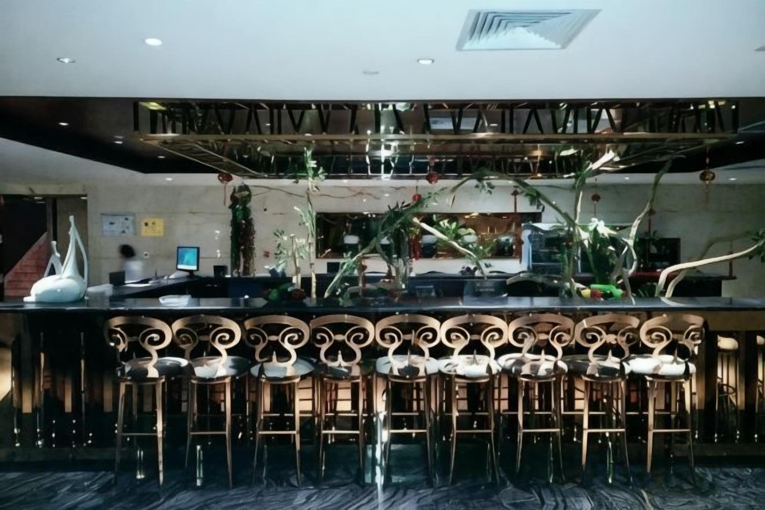 A bar area with a high ceiling, bar stools, and a decorative ceiling design.