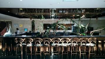 A bar area with a high ceiling, bar stools, and a decorative ceiling design.