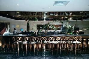 A bar area with a high ceiling, bar stools, and a decorative ceiling design.
