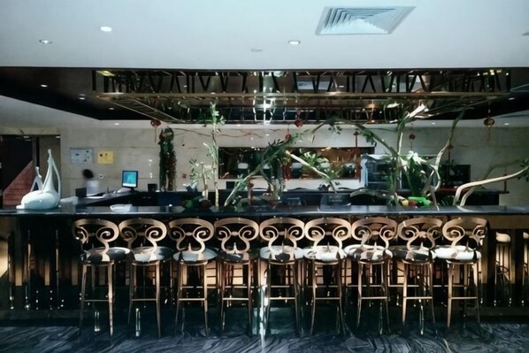 A bar area with a high ceiling, bar stools, and a decorative ceiling design.