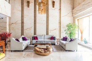A spacious lobby with marble walls, a central seating area with sofas and a coffee table, and a large plant. - Xing Yue Business Club (Tongliao)