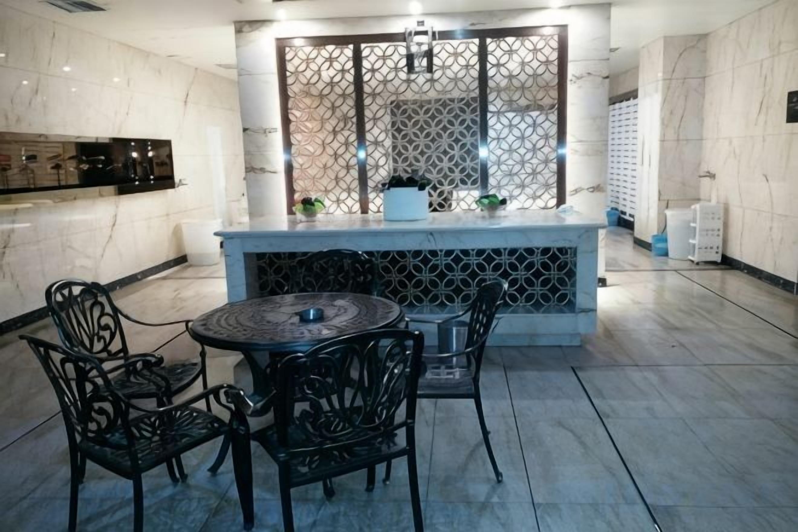 Une cuisine moderne avec un plan de travail en marbre, une table de salle à manger ronde entourée de chaises et un élément de séparation décoratif.