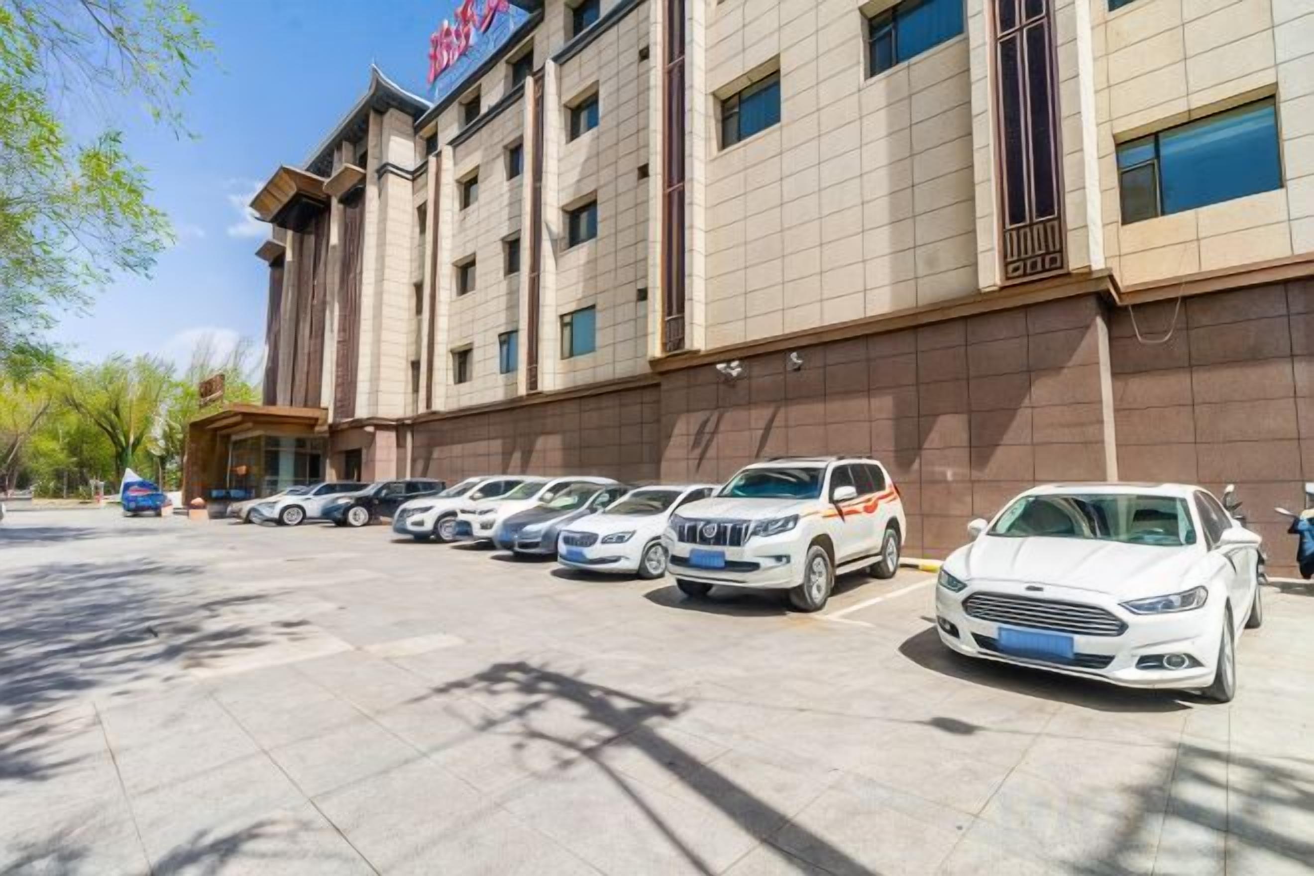 Un hôtel doté d’un parking, de plusieurs voitures et d’une façade.