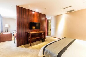 Una habitación de hotel con cama, televisión, escritorio y lámpara.