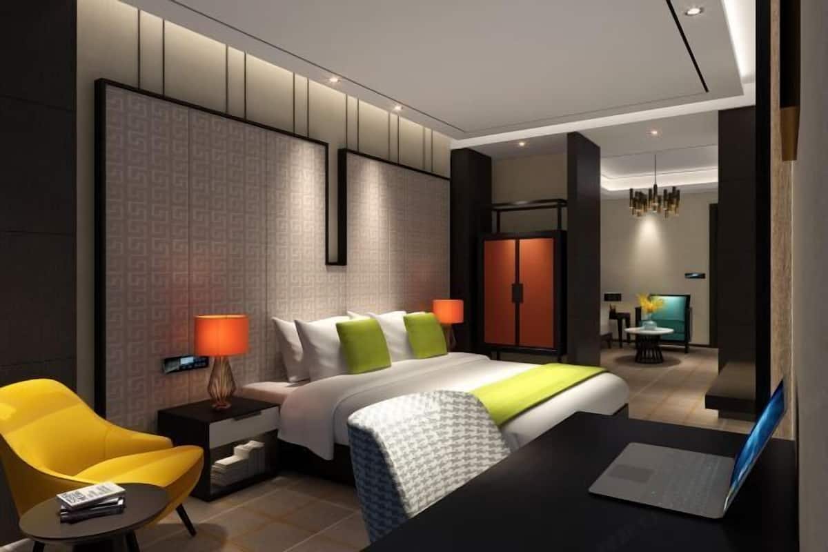Una habitación de hotel moderna con cama, escritorio, silla, televisor y armario.