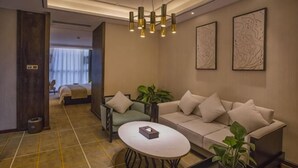 A modern hotel room with a sofa, a coffee table, a plant, and artwork on the wall. - Laimei Hotel (Jianshi)