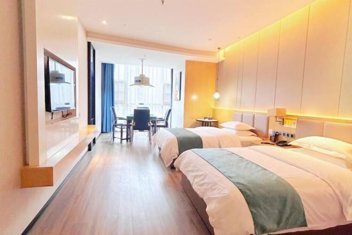 Una habitación de hotel con dos camas, un escritorio, una silla y una televisión.