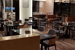 Un salón de conferencias con mesas, sillas, una pizarra y una pantalla de televisión.