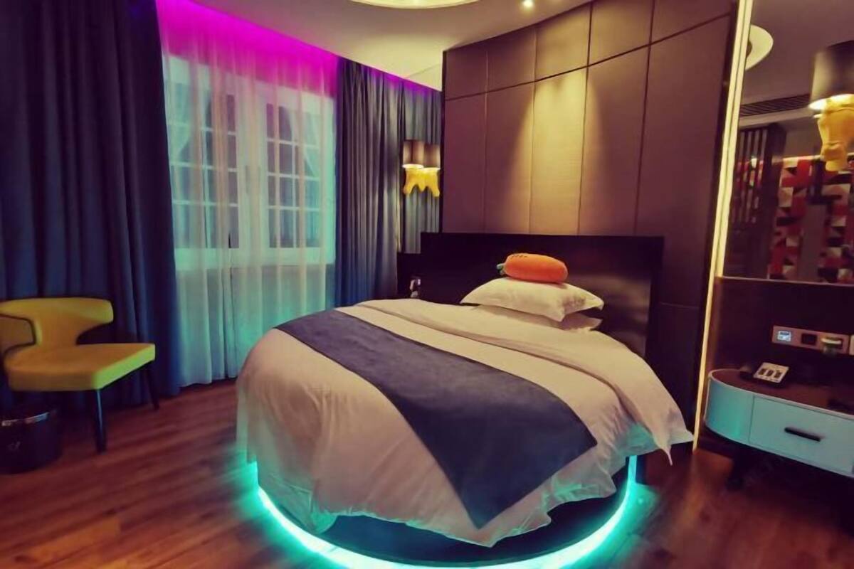 Una habitación de hotel moderna con cama, una silla, armario y espejo.