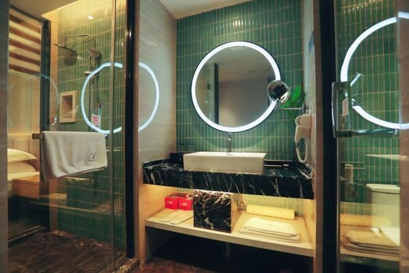 A modern bathroom with a glass-enclosed shower, a round mirror with a light, a sink, and a vanity with toiletries. - Laimei Hotel (Jianshi)