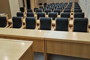 Un salón de conferencias con filas de sillas y una mesa larga.
