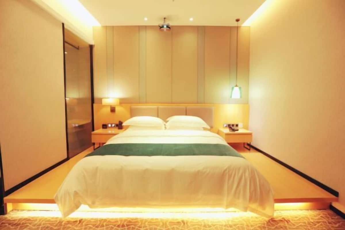 Habitación de hotel con cama, mesitas de noche, lámpara de pared y luz de techo.