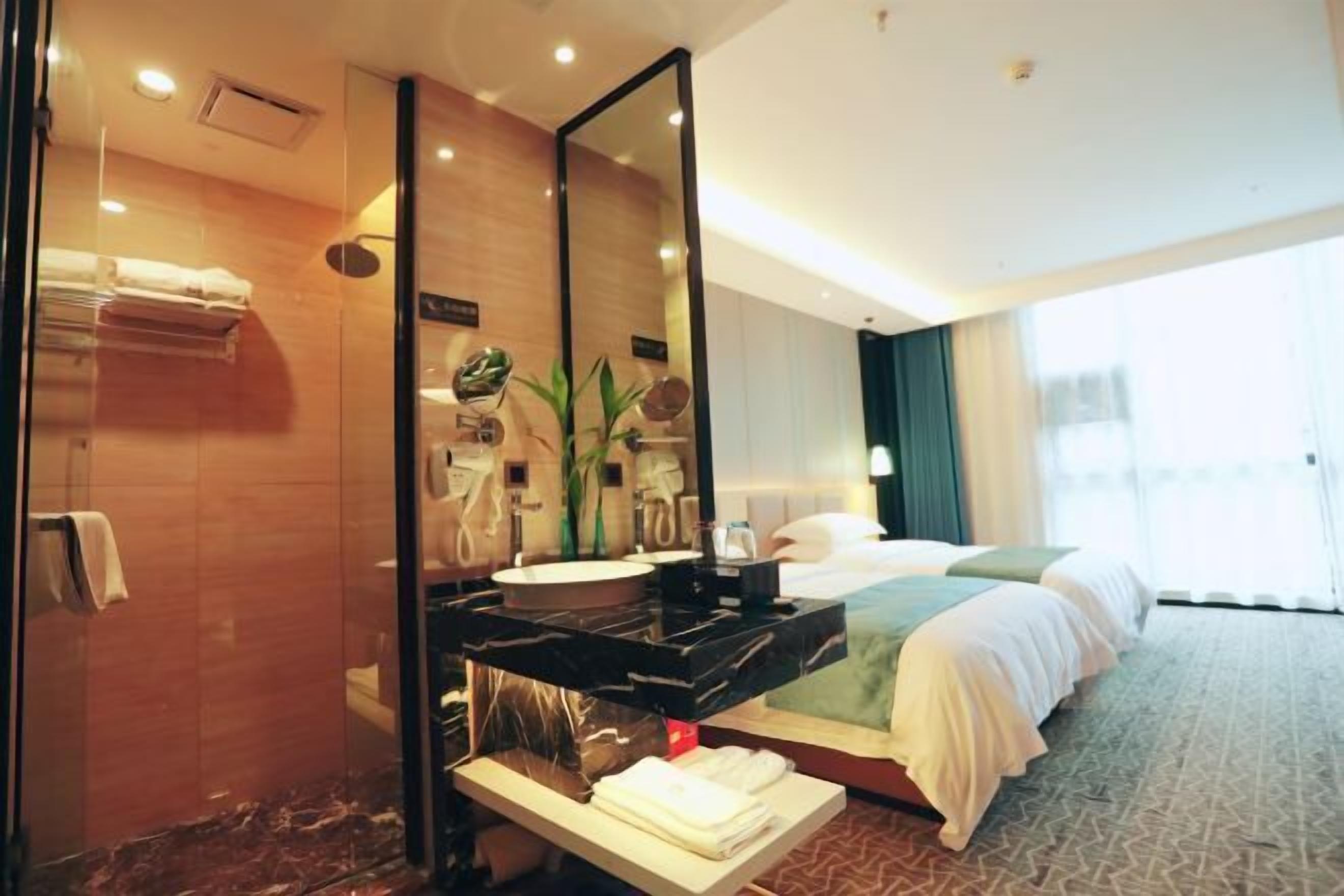 A hotel room with a large mirror, a sink, a bed, and a window.