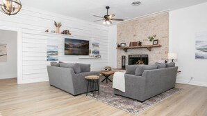 A modern living room with two grey sofas, a wooden coffee table, and a fireplace.