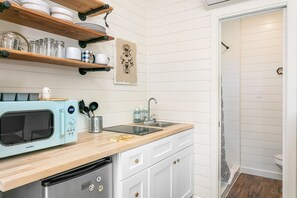 A compact kitchen with a microwave, sink, and storage shelves.