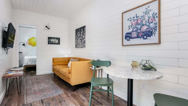 A cozy room with a bed, a yellow sofa, a small table, and a green chair.