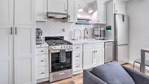 A modern kitchen with white cabinets, a built-in oven, a coffee machine, and a refrigerator. - Walk to Downtown Palm Desert: Home w/ Pool Access (Palm Desert)