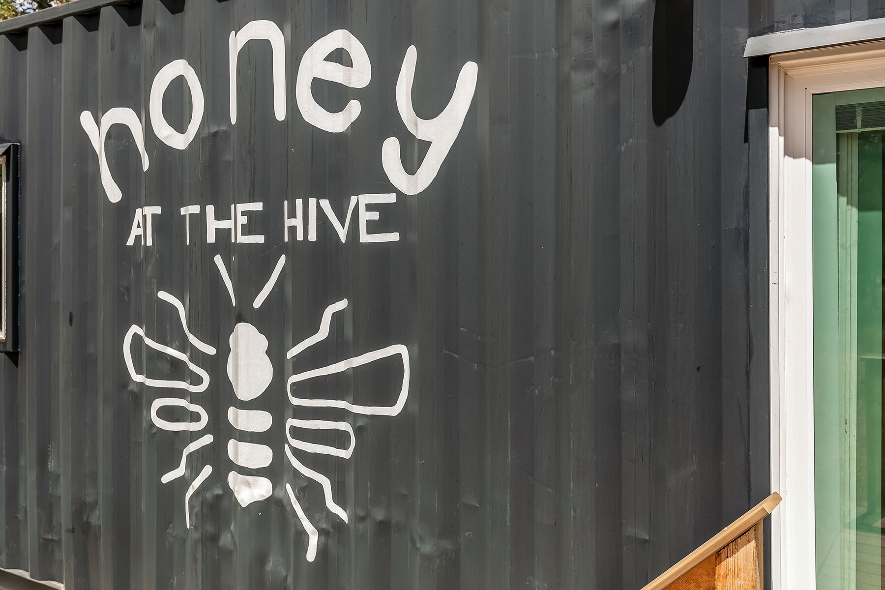 A black exterior wall with white text and a bee illustration.
