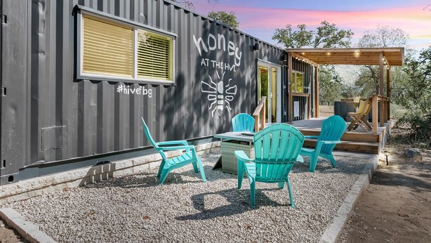 A modern, compact building with a grey exterior and a covered patio area. - Honey at the Hive, 1/1 | Private Hot Tub | Gas Fire Pit | Cornhole (Fredericksburg)