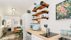 A modern kitchen with wooden shelves, a microwave, a toaster, and a sink. - Honey at the Hive, 1/1 | Private Hot Tub | Gas Fire Pit | Cornhole (Fredericksburg)