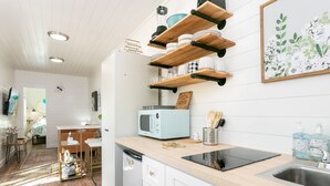 Une cuisine avec des étagères en bois, un four à micro-ondes, un grille-pain et un évier.