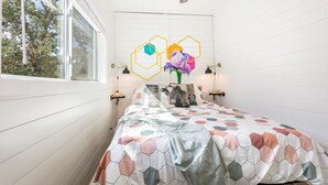 Une chambre à coucher avec un lit, un ventilateur de plafond, une fenêtre et un mur orné de motifs géométriques.