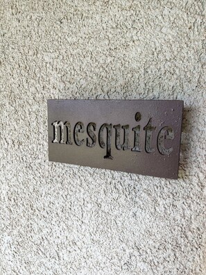 Une plaque portant le mot « mesquite » est fixée à un mur à texture.