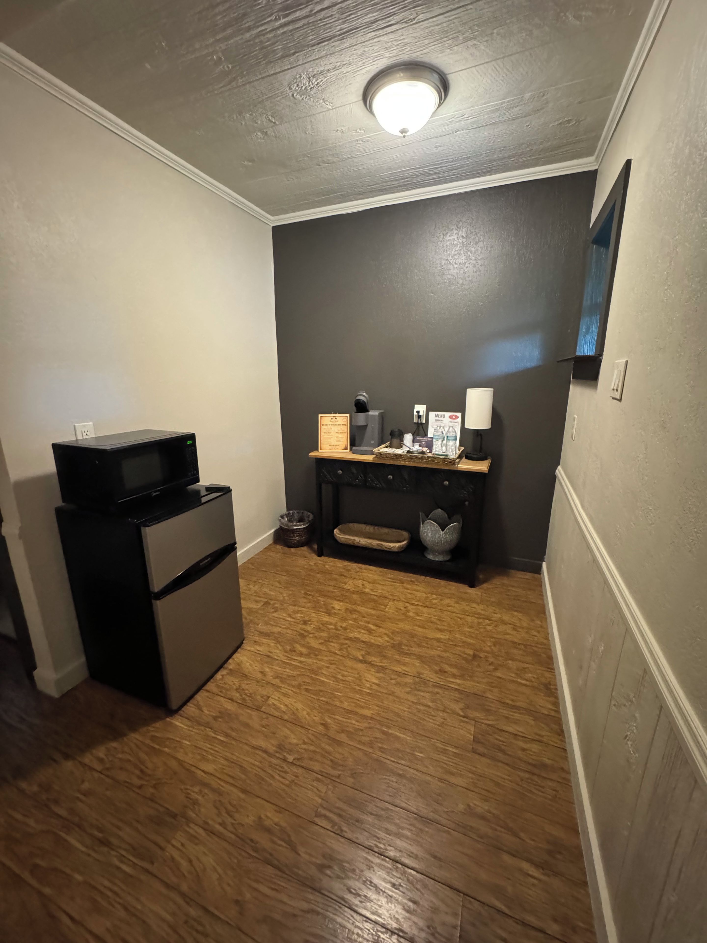 A compact room with a kitchenette, a small seating area, and a ceiling light.