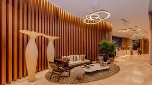 A modern lobby with a wooden slat wall, a sofa with cushions, a coffee table, and tall floor lamps. - Amazing apartment Lyfe Resort-& Residences- Ocean view! (Hollywood)