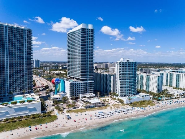 Un paysage urbain côtier avec de hauts immeubles, une plage et un port de plaisance.